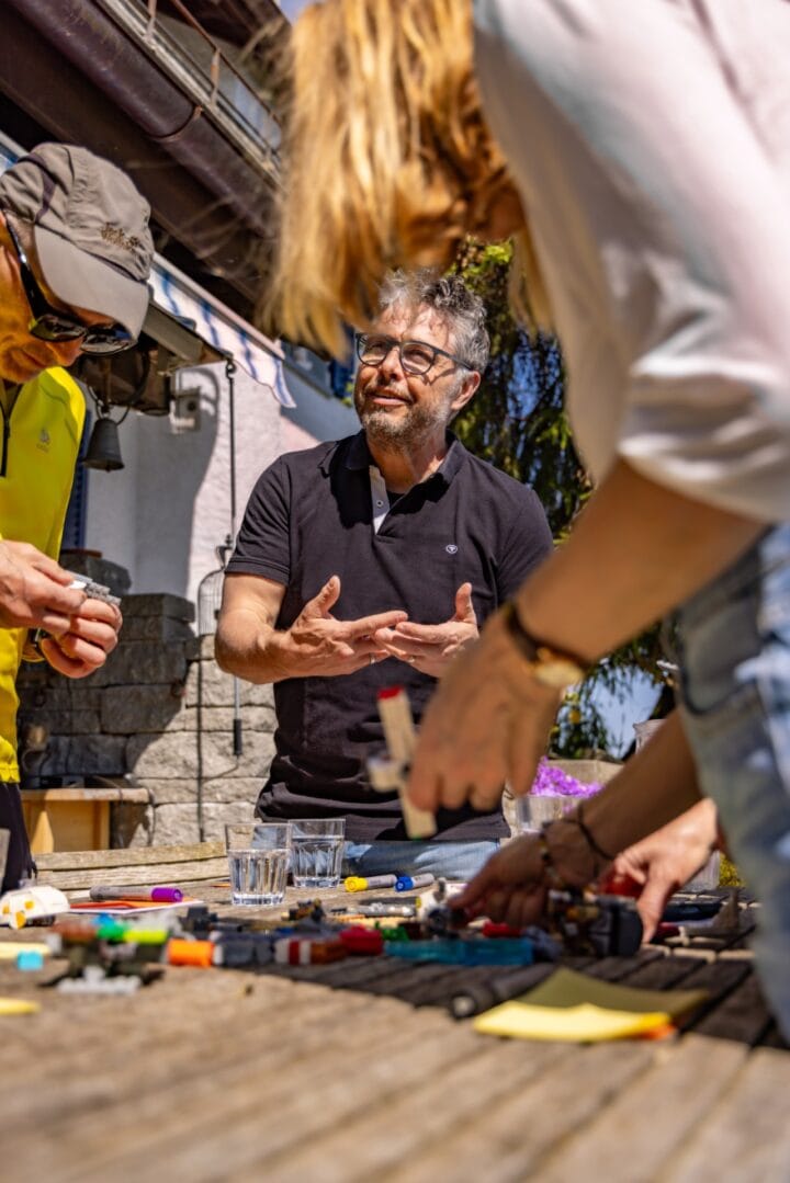 Menschen bauen zusammen draußen mit bunten Bausteinen.
