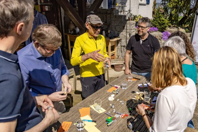 Gruppe diskutiert um Tisch im Freien.