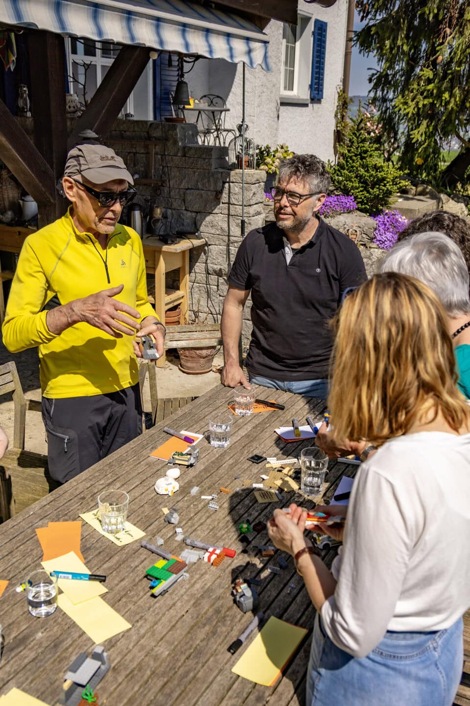 Gruppe diskutiert am Tisch mit Legosteinen und Notizen.